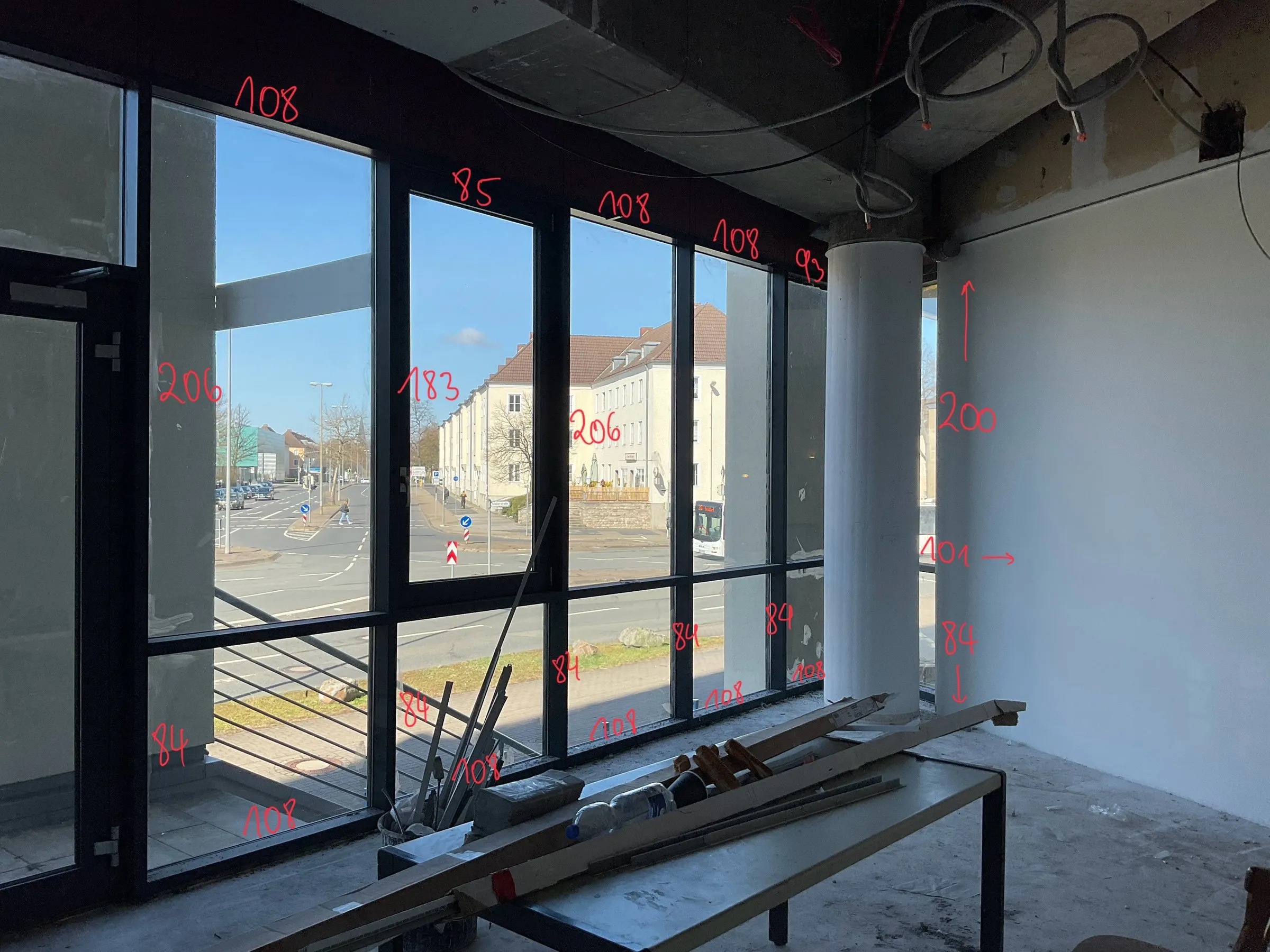 Fensterfront im Rohbau mit eingezeichneten roten Maßen auf den Scheiben