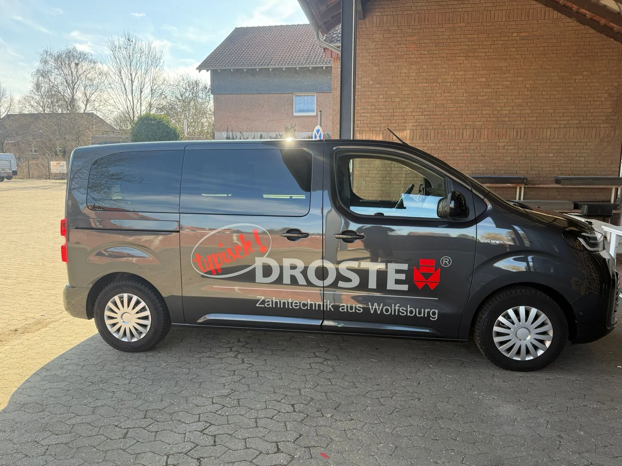 Grauer Toyota Proace mit Schriftzug und Logo von Droste Zahntechnik