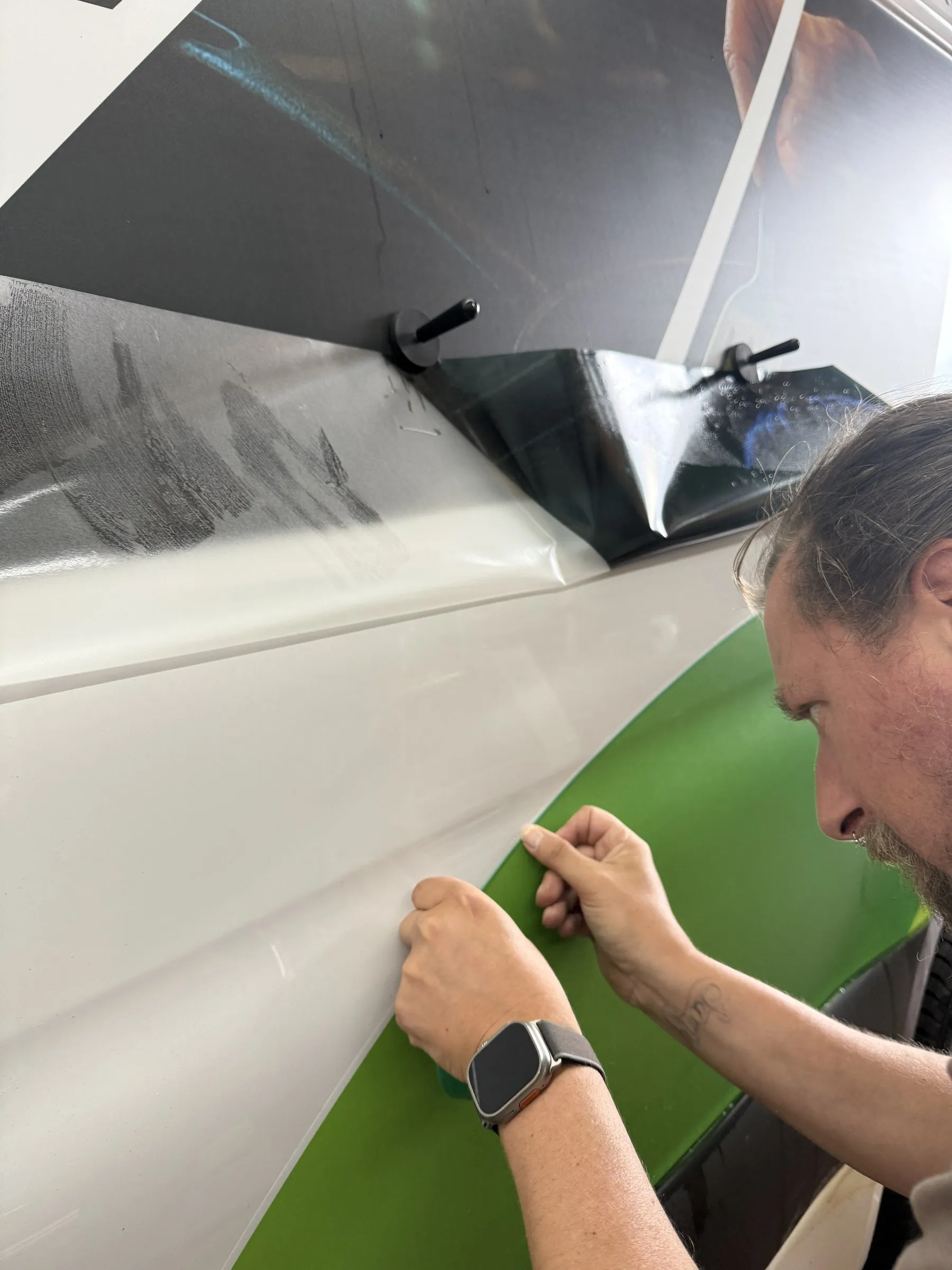 Grüne Fahrzeugfolie wird von Hand an der Seitenwand eines Sprinters verklebt