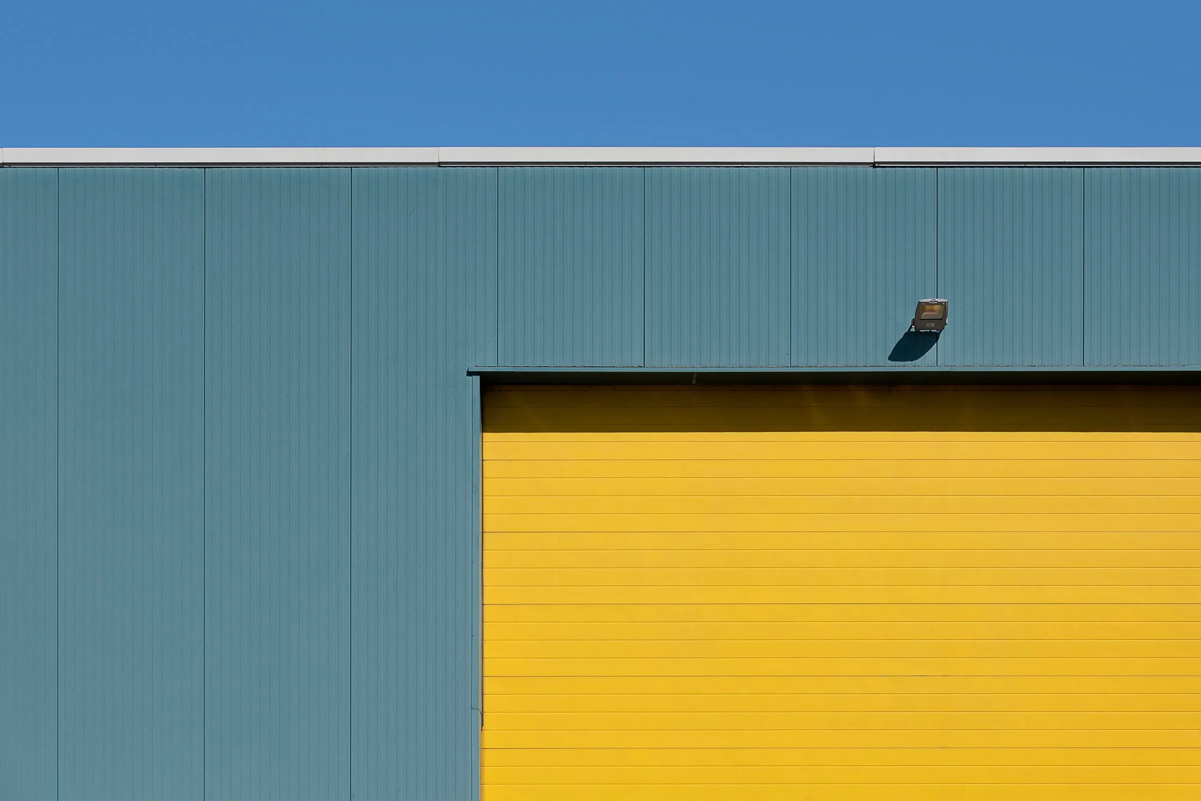 Hallenwand mit petrolfarbenen Paneelen und gelbem Rolltor