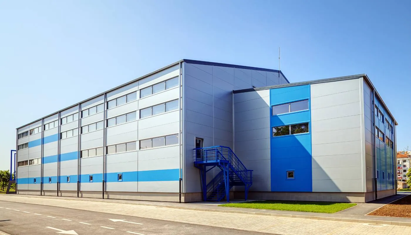 Industriehalle mit silbernen Paneelen und blauen Farbbändern
