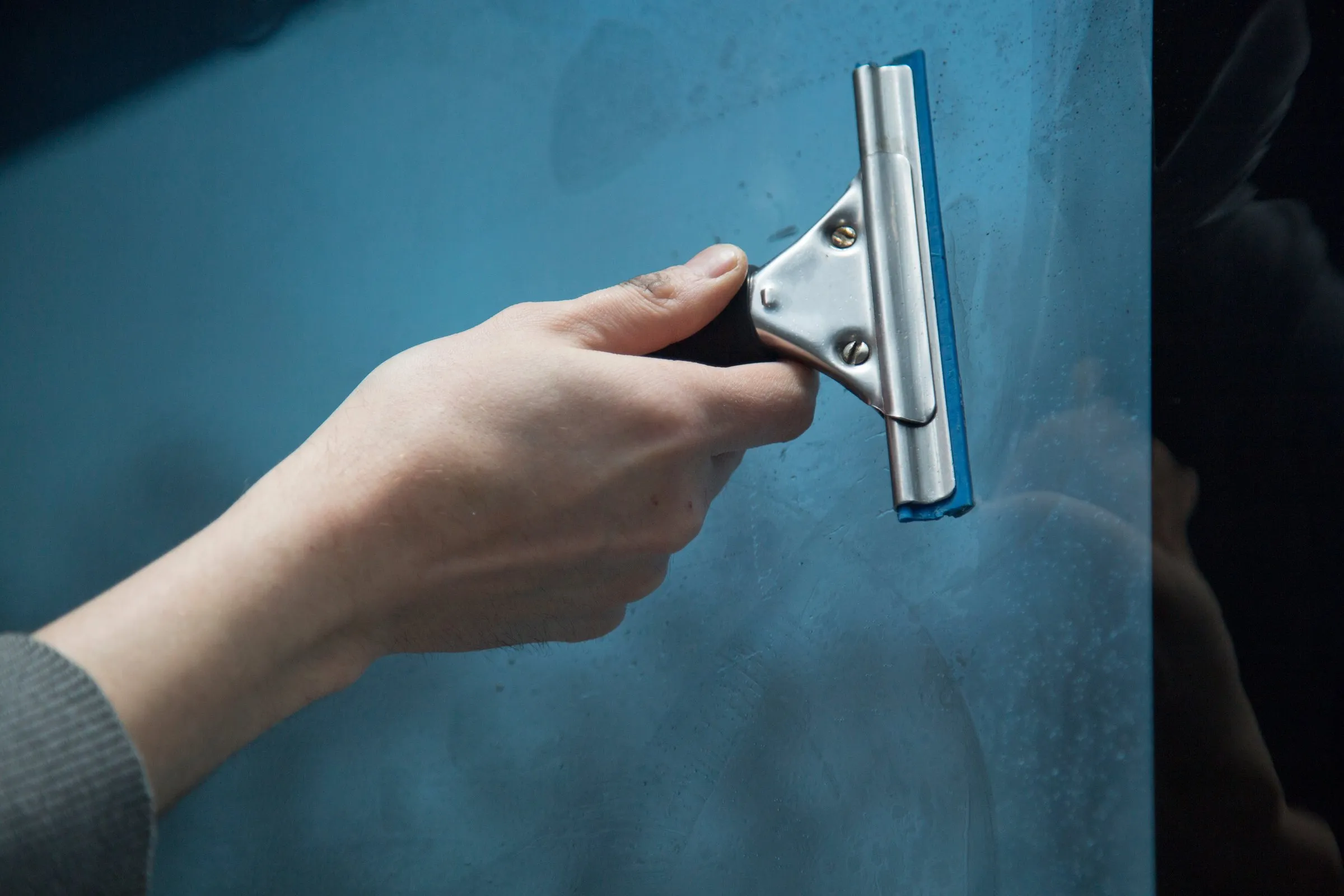 Getönte Fensterfolie wird mit dem Rakel blasenfrei verklebt