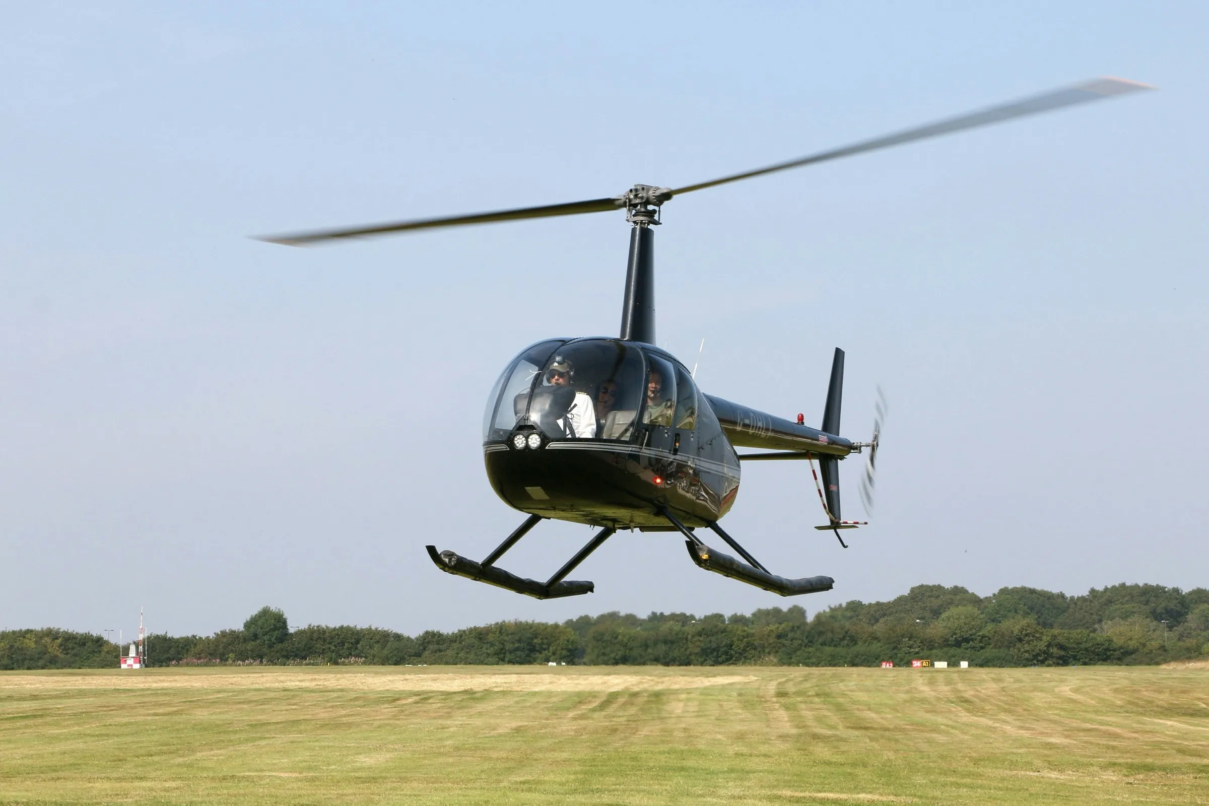 Schwarzer Hubschrauber schwebt knapp über einer Graspiste