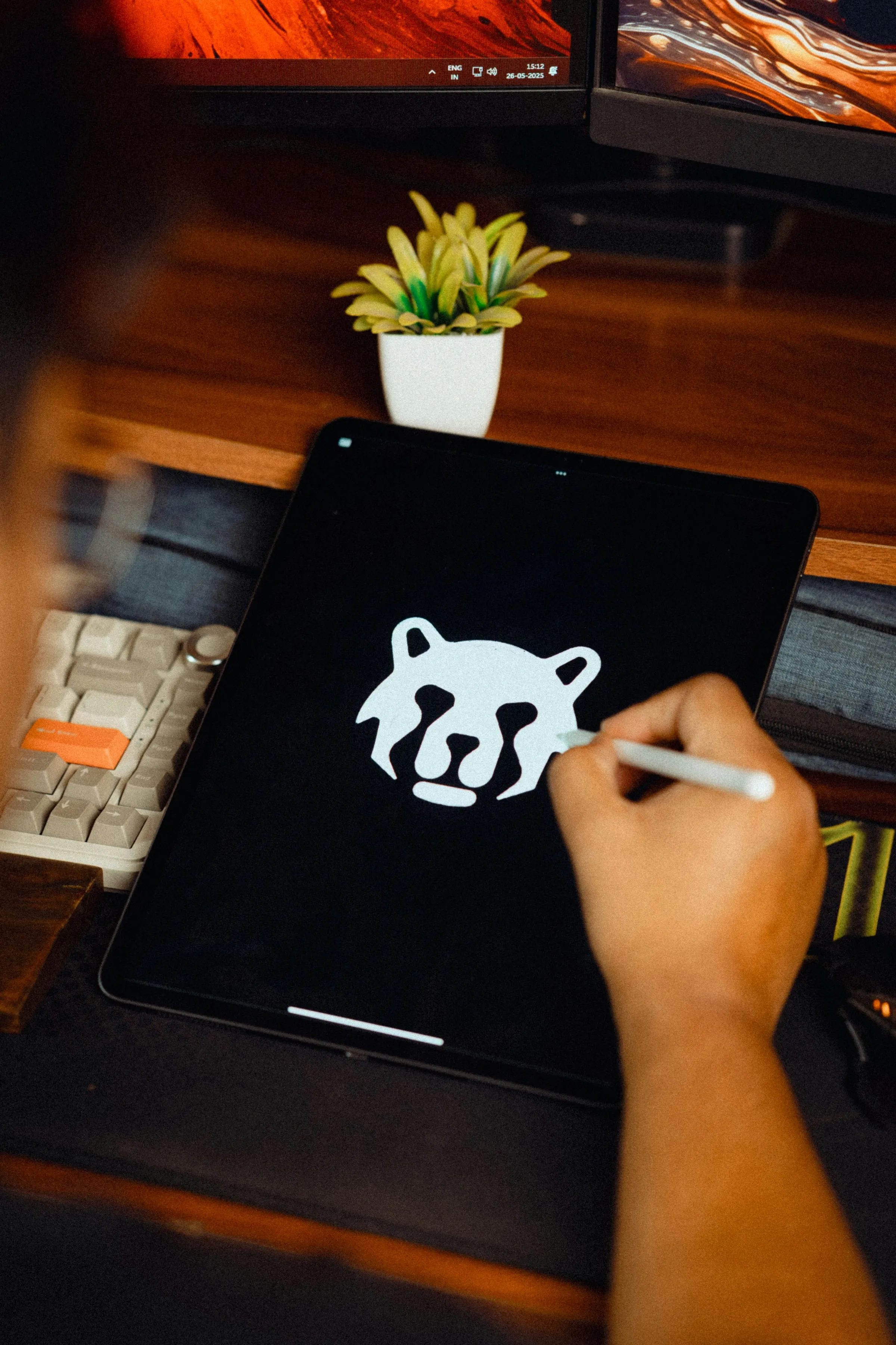 Hand mit Stift arbeitet an einem flächigen Tierlogo auf einem Tablet