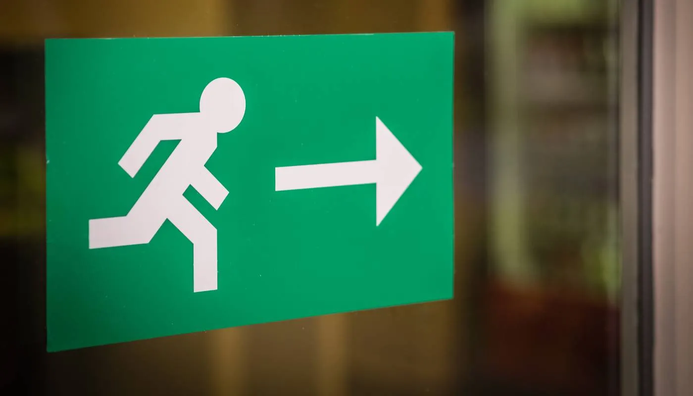 Grünes Rettungswegschild mit laufendem Männchen und Pfeil