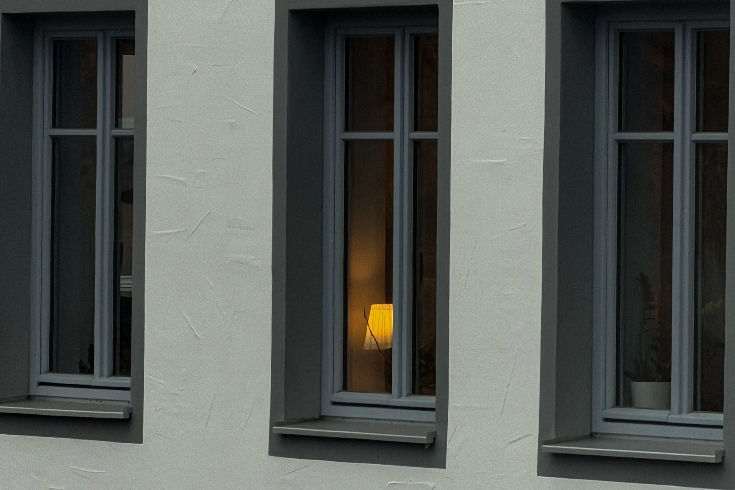 Drei schmale Fenster mit anthrazitgrauen Rahmen und Fensterbänken in einer weißen Hausfassade