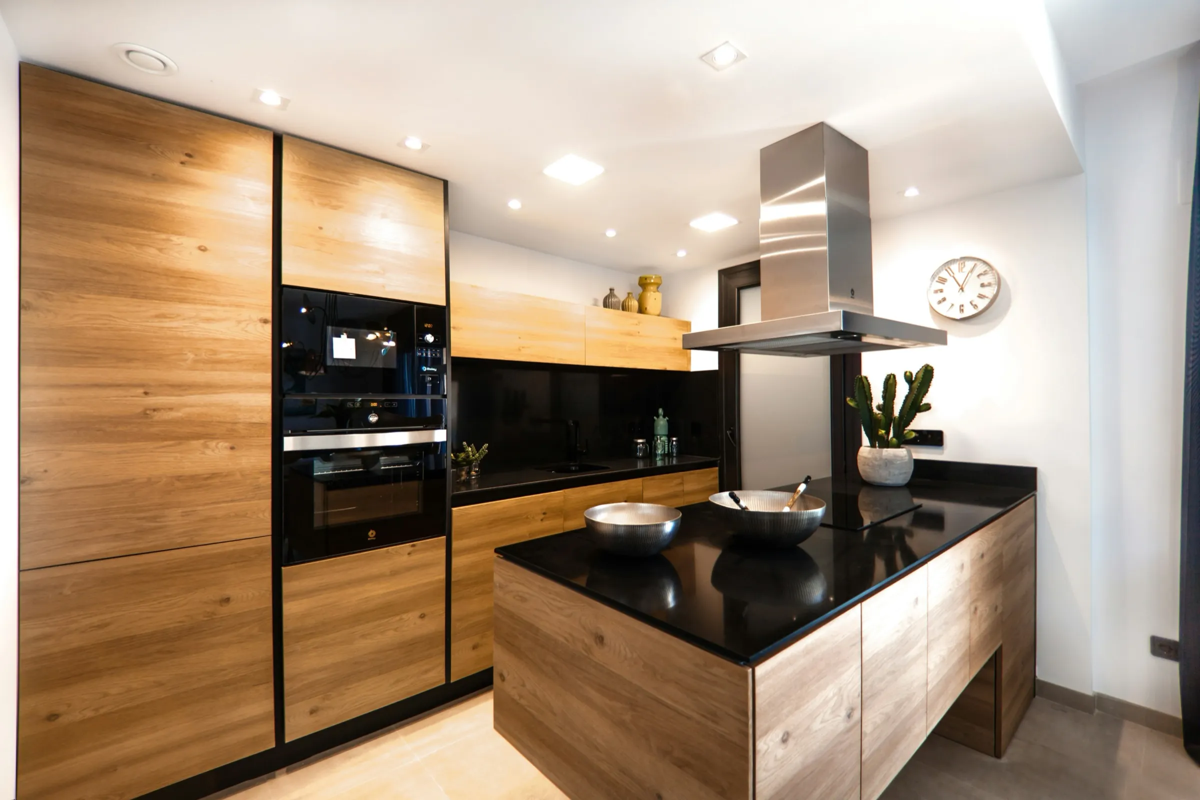 Moderne Küche mit Fronten in Holzoptik, Kücheninsel und schwarzer Arbeitsplatte