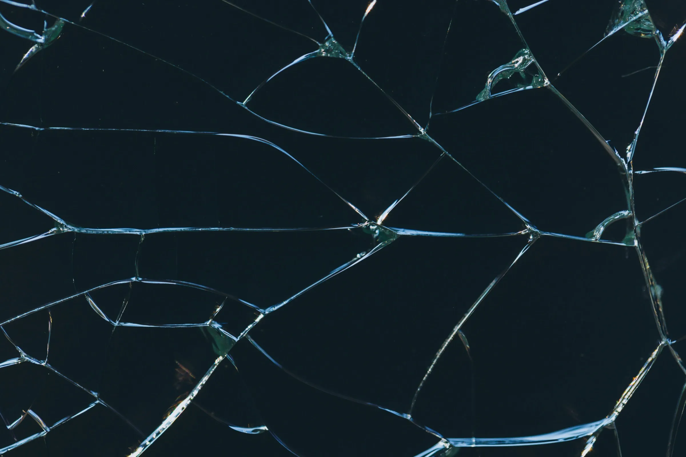 Nahaufnahme einer gerissenen Glasscheibe vor dunklem Hintergrund