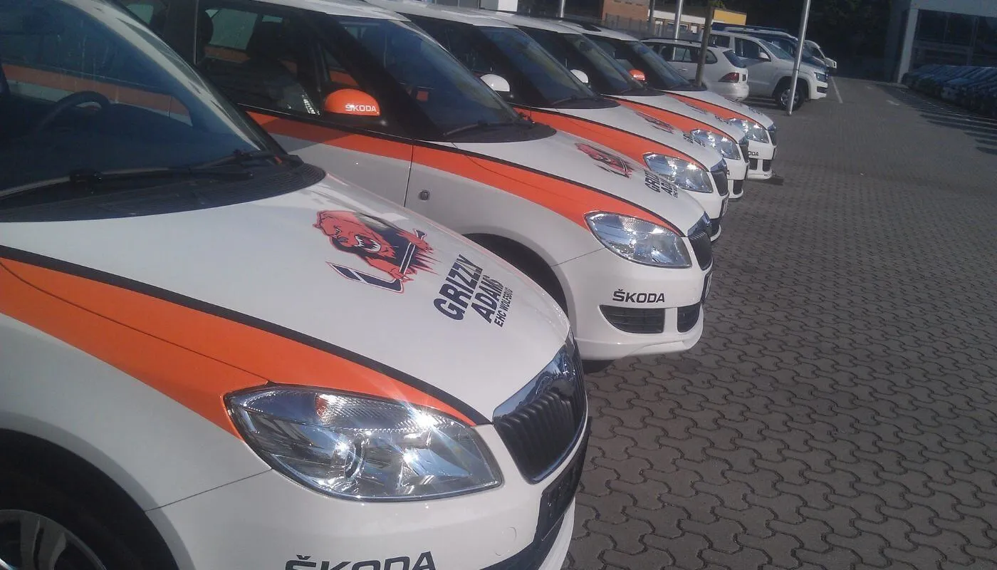 Reihe gleich beschrifteter Skoda Fabia mit orangen Streifen und Logo der Grizzly Adams Wolfsburg