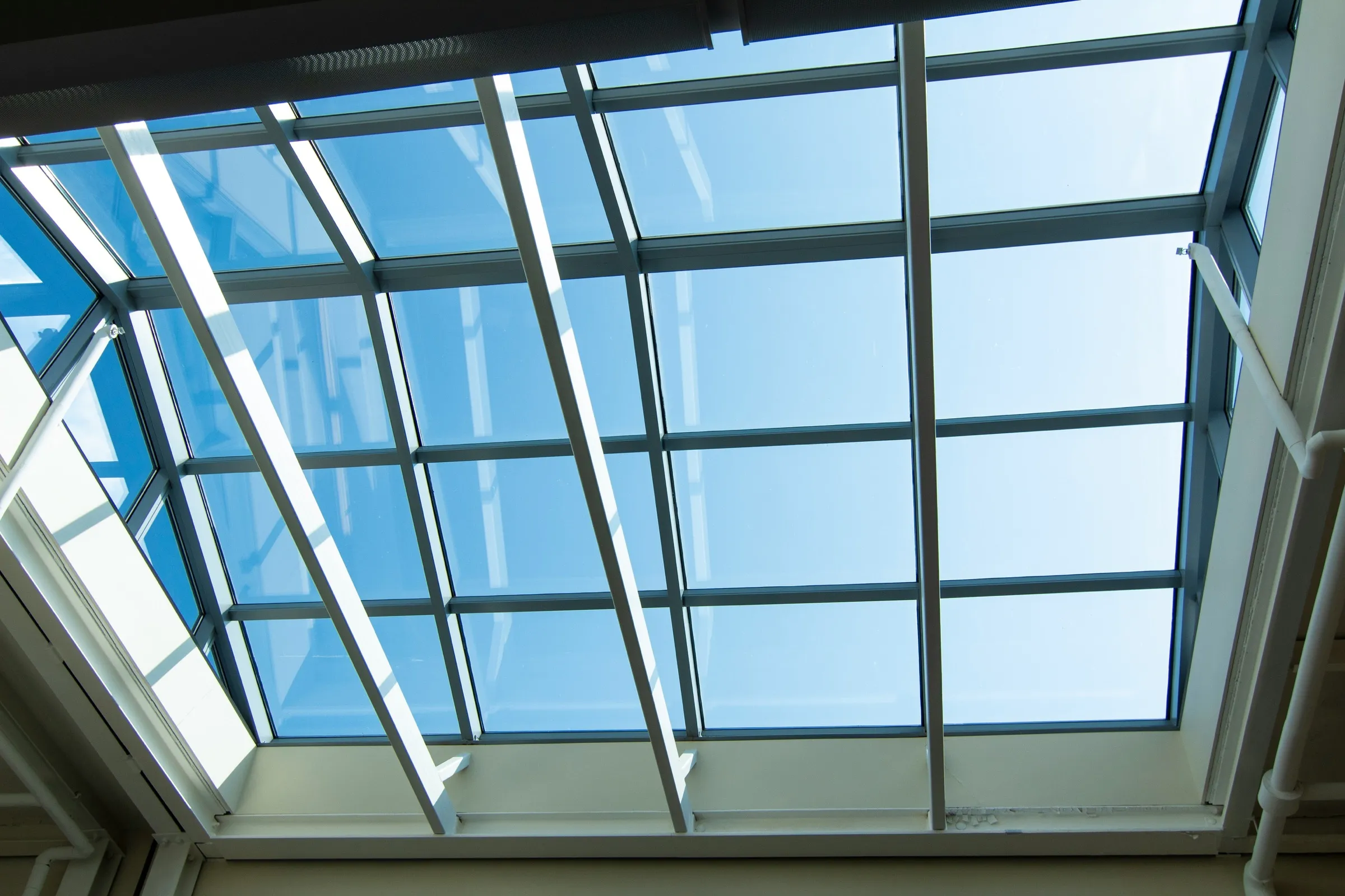 Glasdach mit weißen Sprossen, Blick von unten in den blauen Himmel