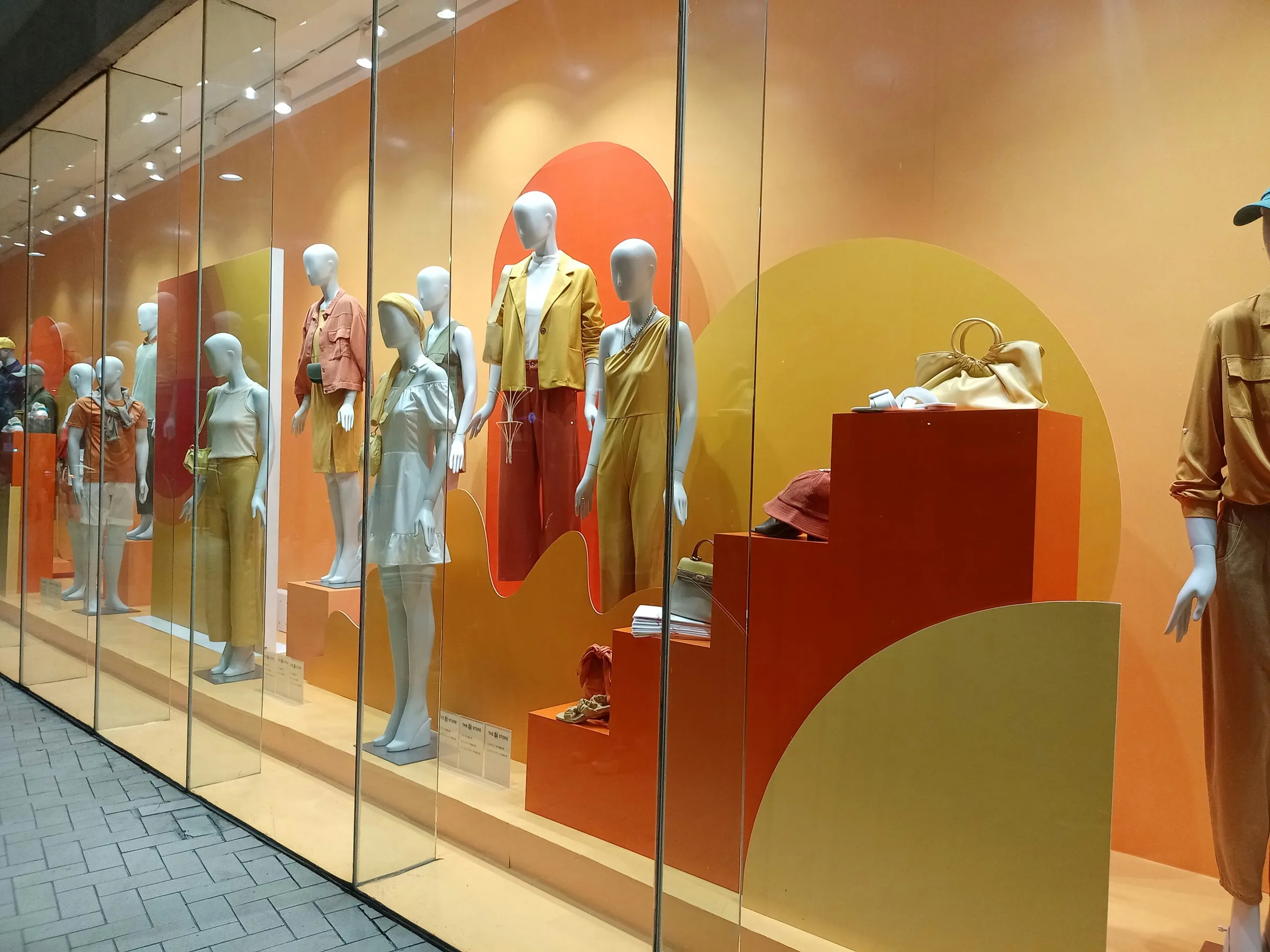 Schaufensterfront eines Modegeschäfts mit Schaufensterpuppen in warmen Farben