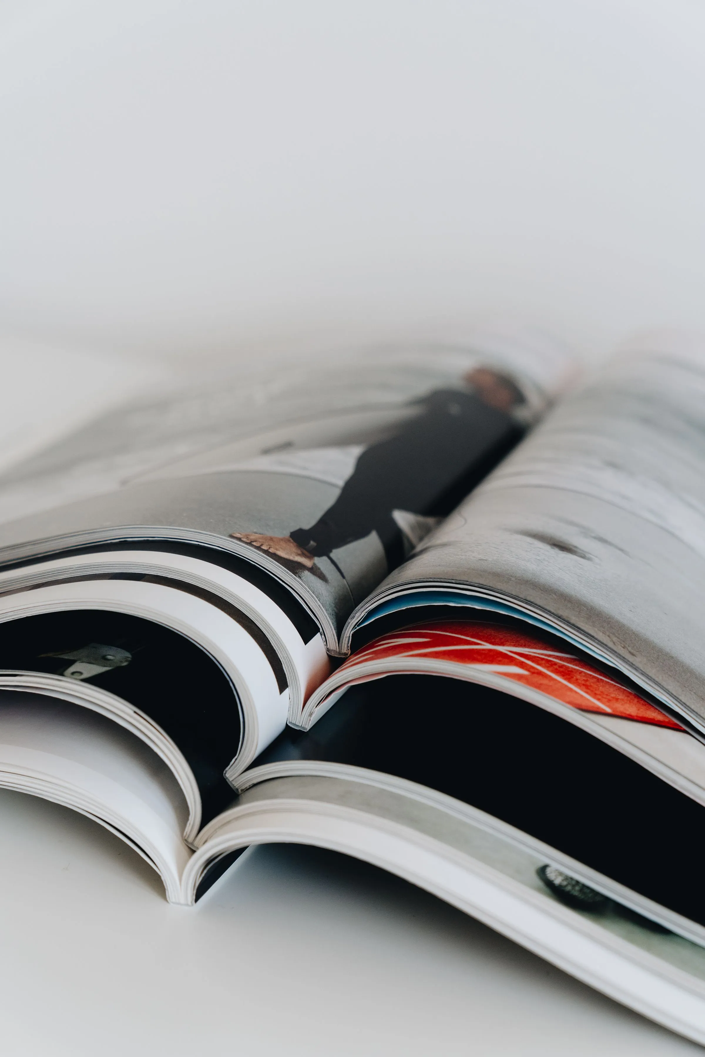 Mehrere aufgeschlagene Magazine liegen übereinander auf hellem Grund