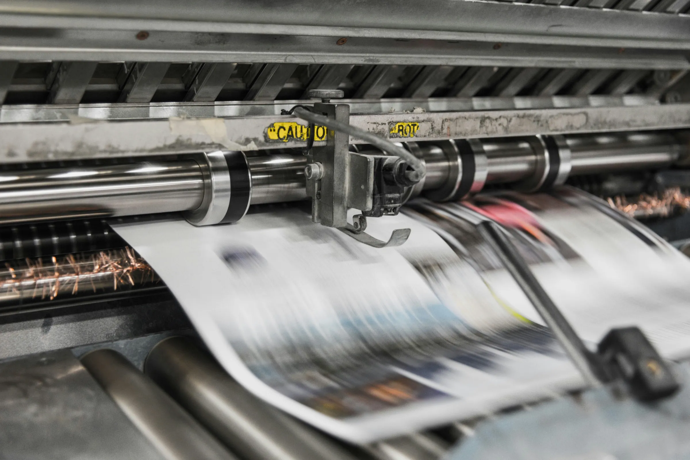 Bedrucktes Papier läuft in schneller Bewegung über die Walzen einer Druckmaschine
