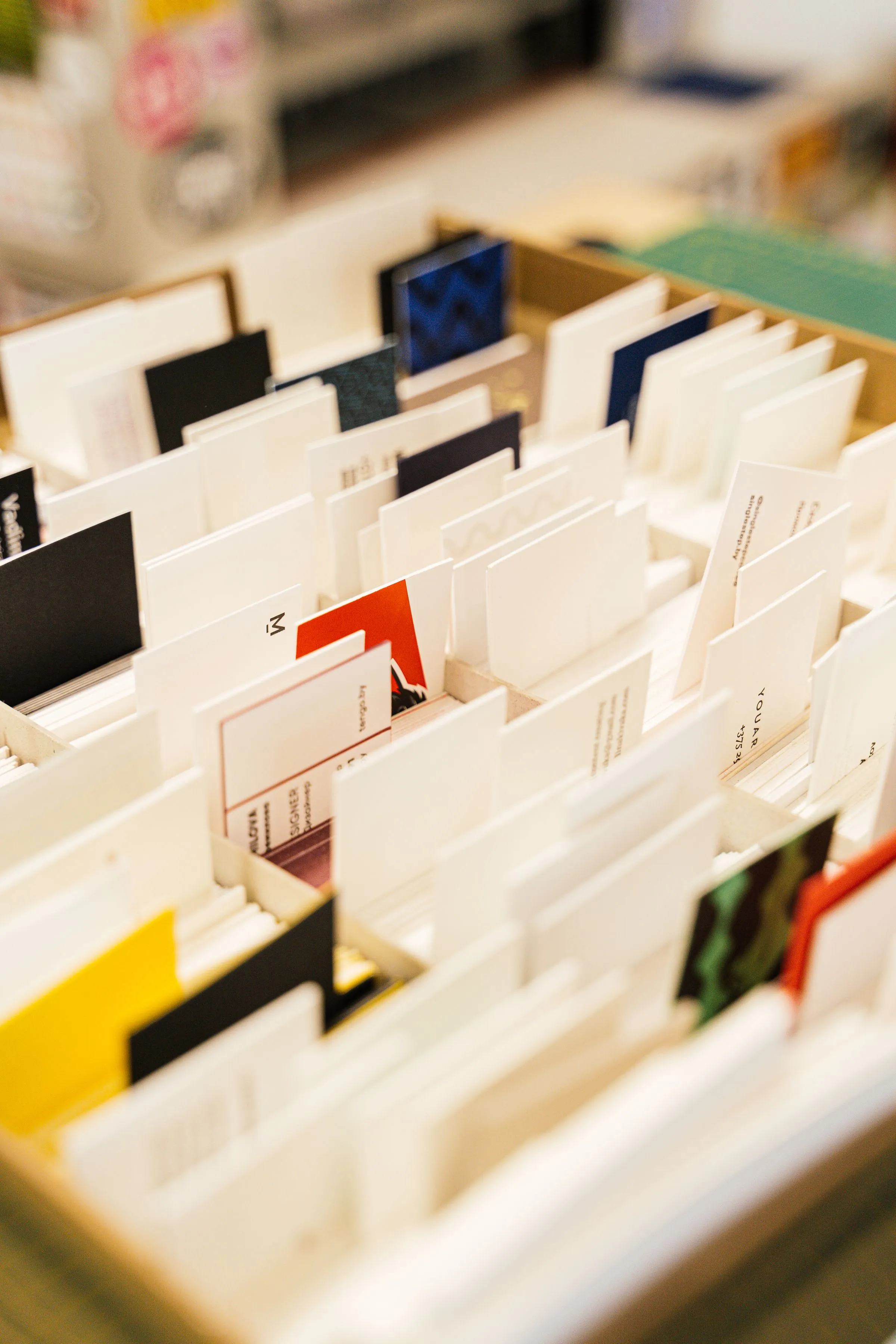 Viele unterschiedliche Visitenkarten aus verschiedenen Papieren und Farben stehen sortiert in einer Box