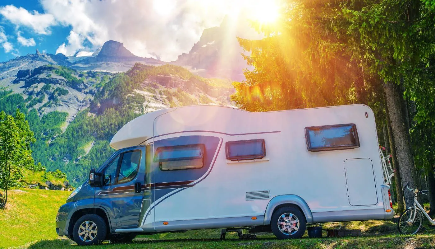 Wohnmobil mit blau-grauer Seitengrafik auf einer Wiese vor Bergen