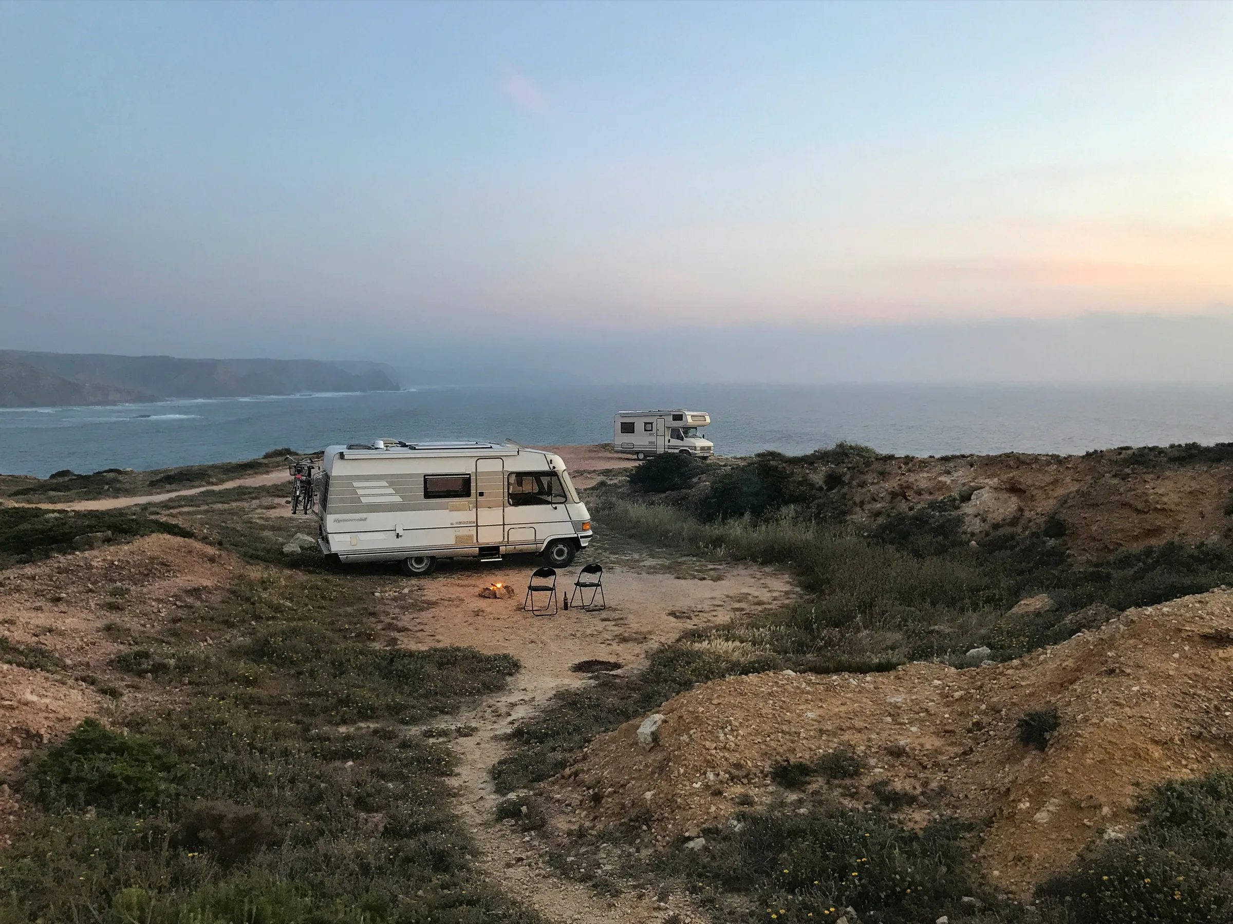 Älteres Wohnmobil mit Seitenstreifen auf einem Stellplatz an der Küste in der Abenddämmerung